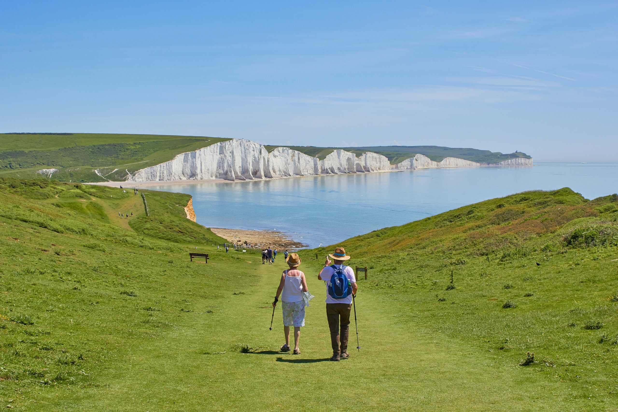 Couple hiking on a grassy path near water during their retirement