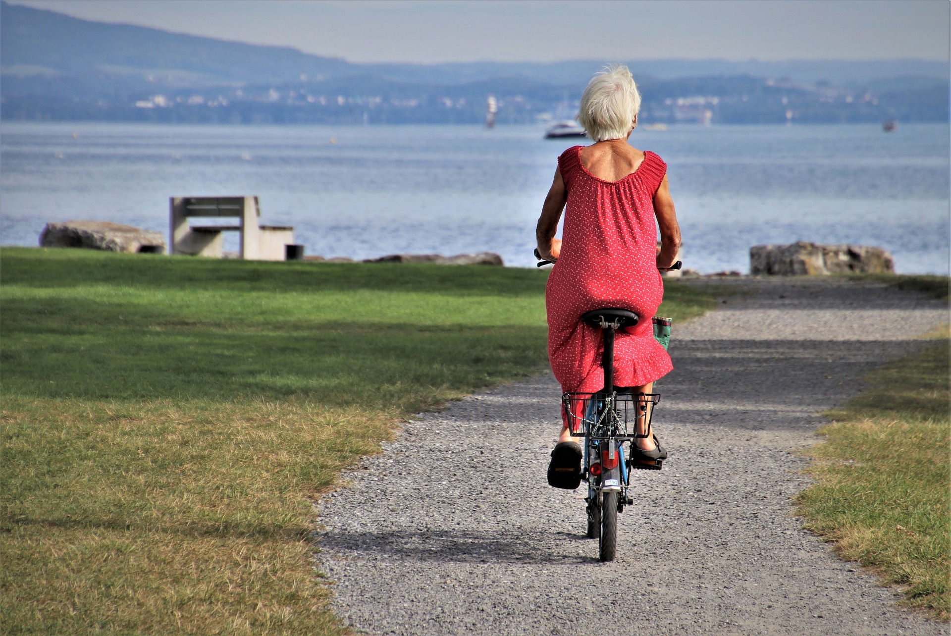 Retired women riding a bike down a path near water