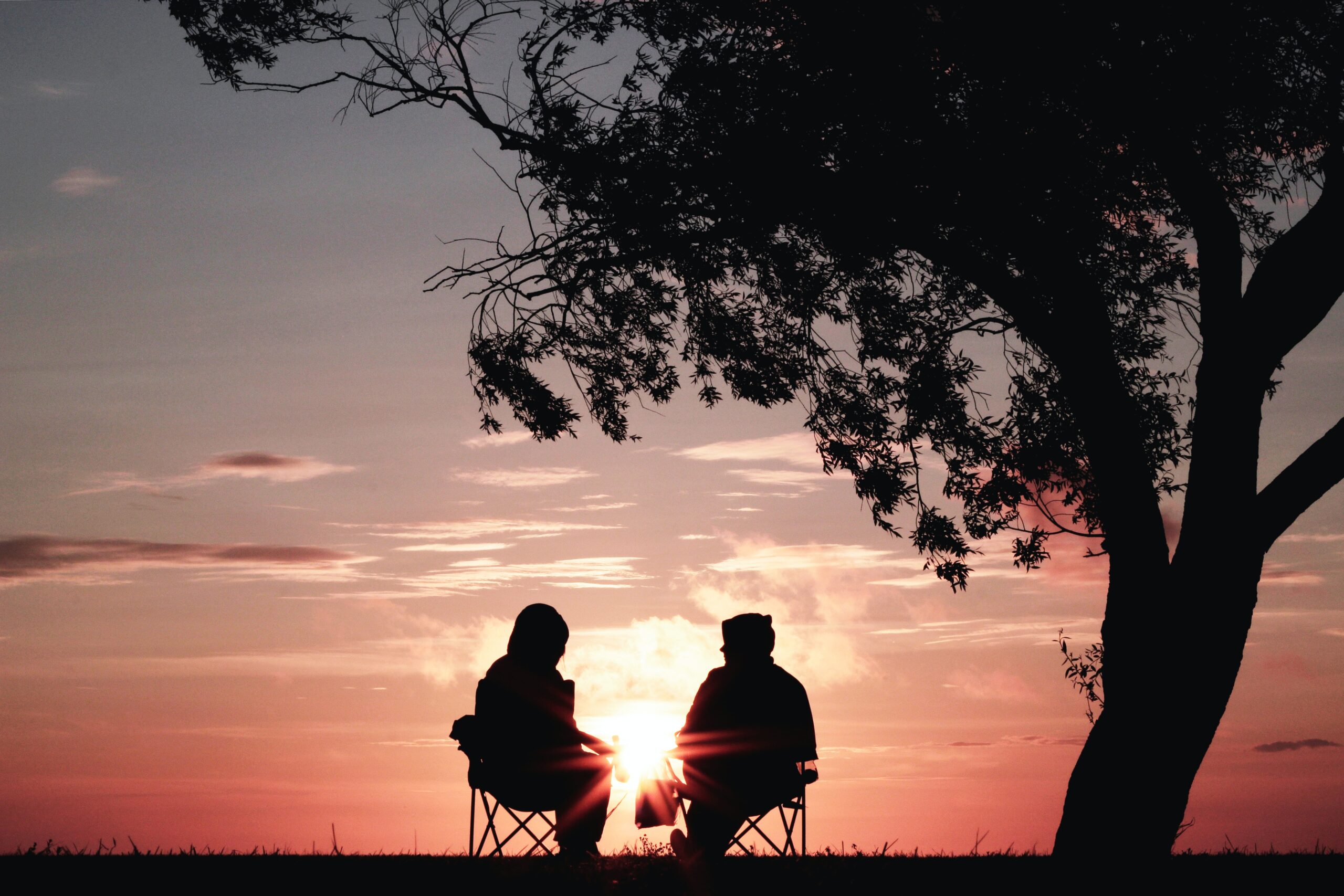 two old people staring out at the sunset